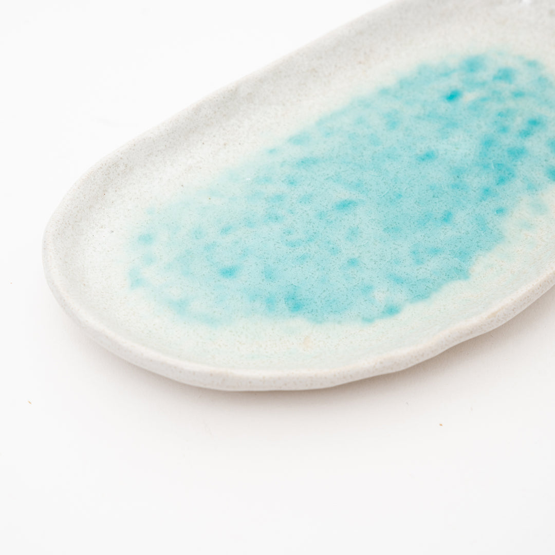 A close-up of a Seto ware oval dish, showing the detail of the turquoise flowing glaze and the natural ceramic body, an elegant piece for home decor.