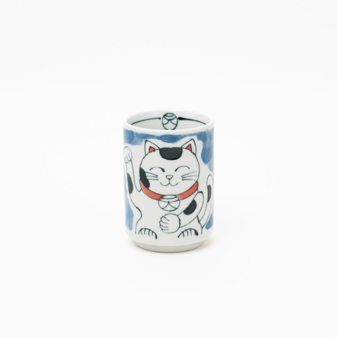 Front view of an authentic Japanese Maneki-Neko lucky cat porcelain cup with a hand-painted white cat, red collar, and blue background wash.