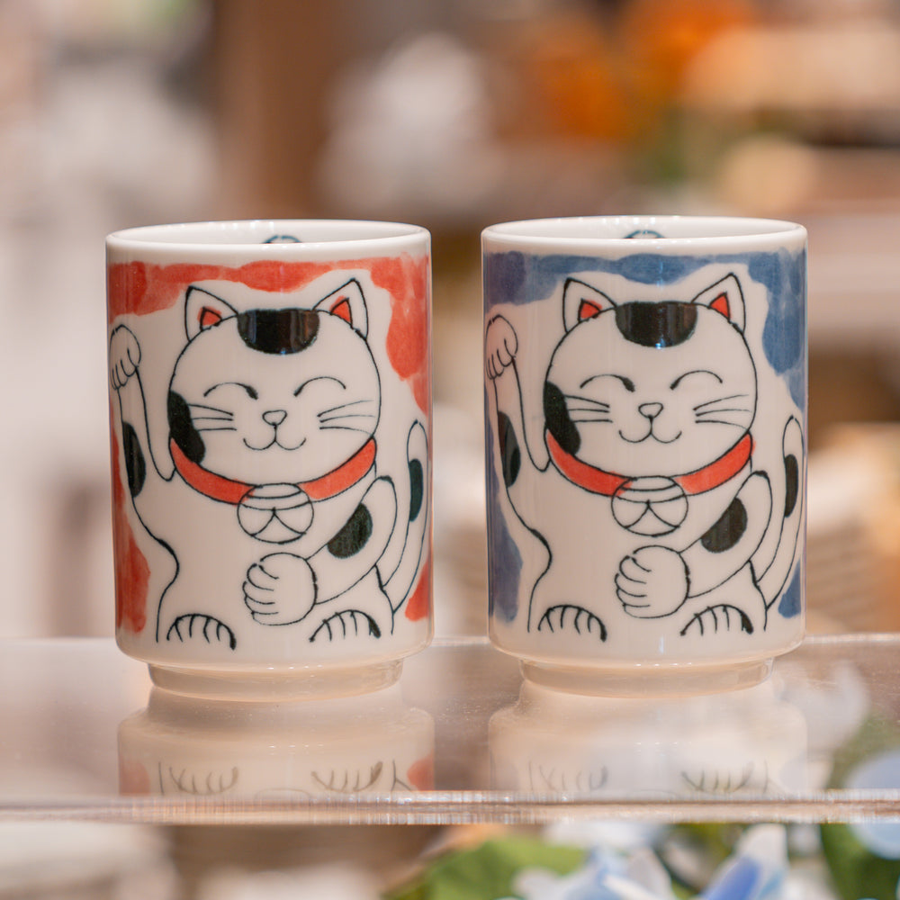 Two ceramic cups with cat illustrations on a blurred background