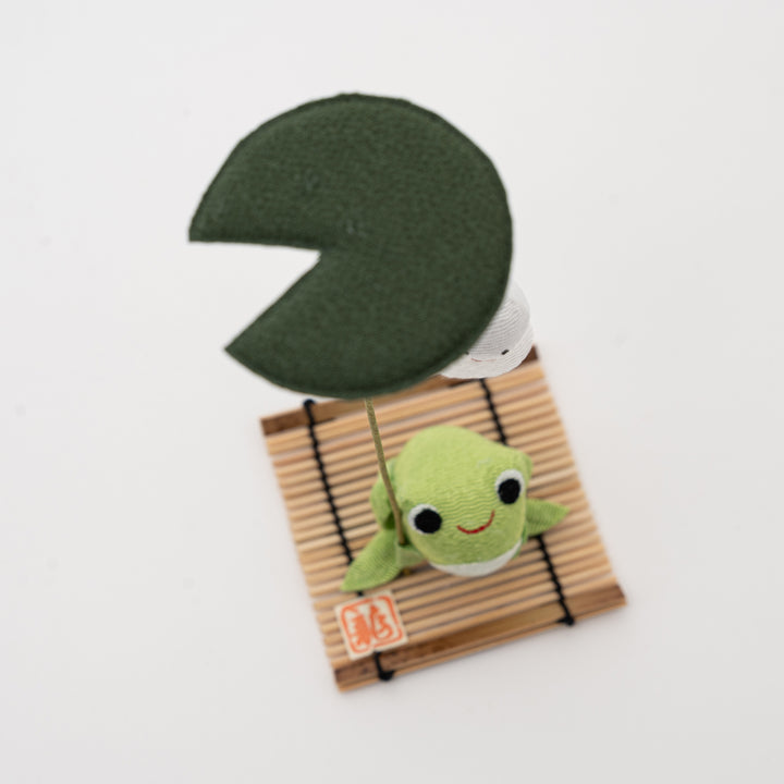 Close-up top-down view of the Ryukodo frog figurine, showing the nylon cloth texture, bamboo base, and green leaf umbrella