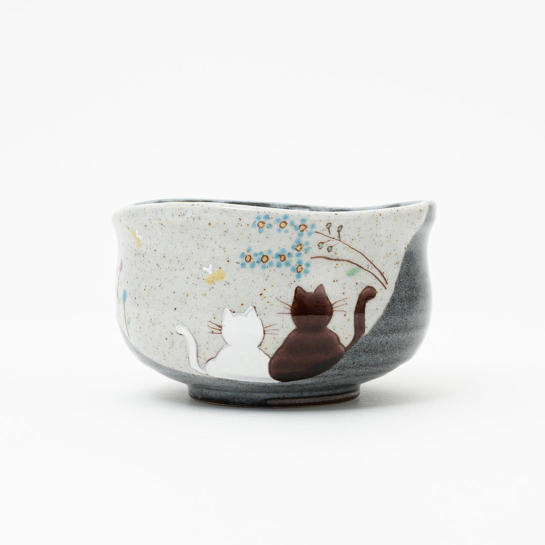 Hand-painted Kutani Ware matcha bowl from Japan, featuring two cats gazing at blue flowers and a butterfly on a speckled background.