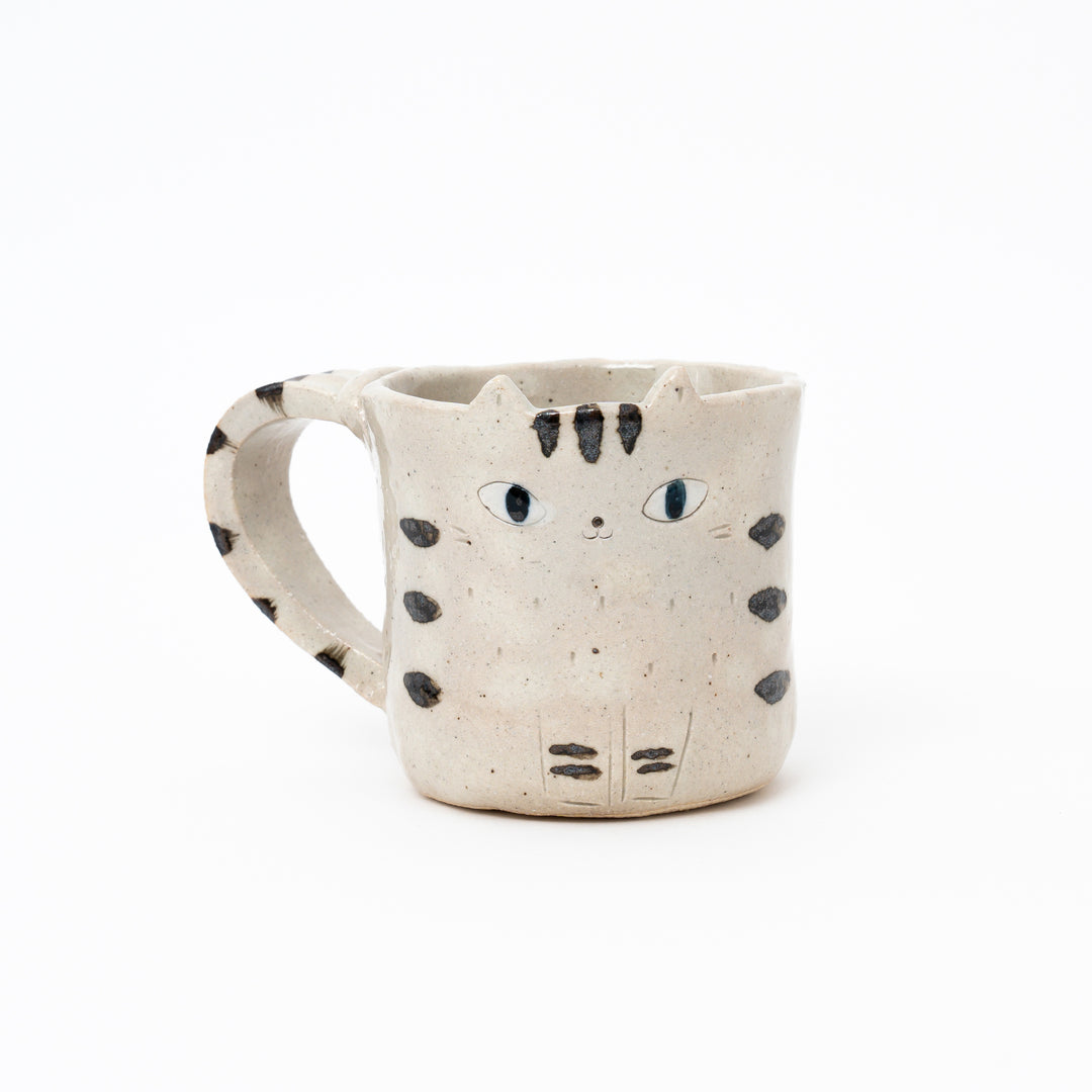 Handcrafted Japanese ceramic mug with a speckled tabby cat design, black stripes/spots, and black eyes