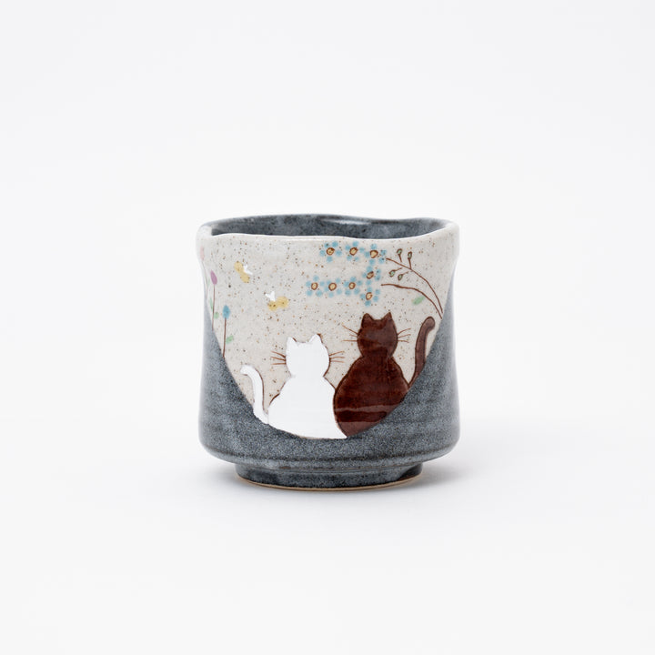 Hand-painted Kutani Ware Japanese ceramic tea cup (yunomi) with a serene design of two cats gazing at blue flowers on a speckled and dark gray glazed background.