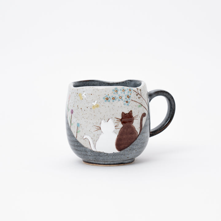 Hand-painted Kutani Ware Japanese ceramic coffee mug with a serene design of two cats gazing at blue flowers on a speckled and dark gray glazed background.