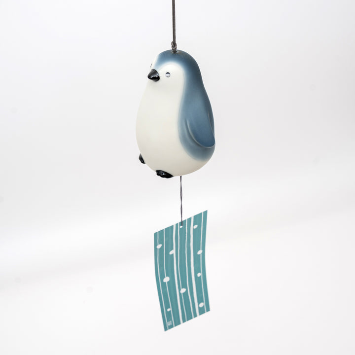 Close-up view of a Yakushigama penguin wind chime, showing the detailed ceramic glaze and cute face, placed in a home setting