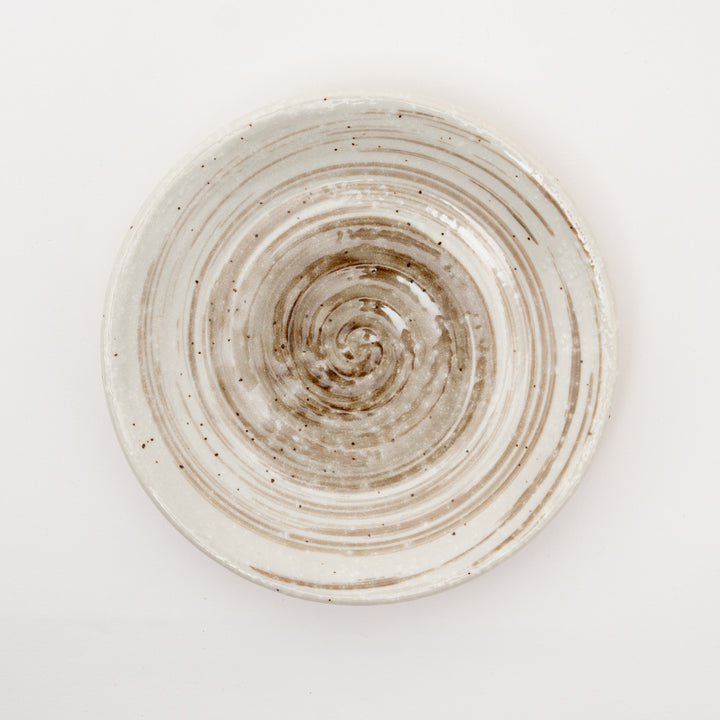 Close-up of spiral pattern ceramic sauce dish showing concentric circles and speckled glaze texture