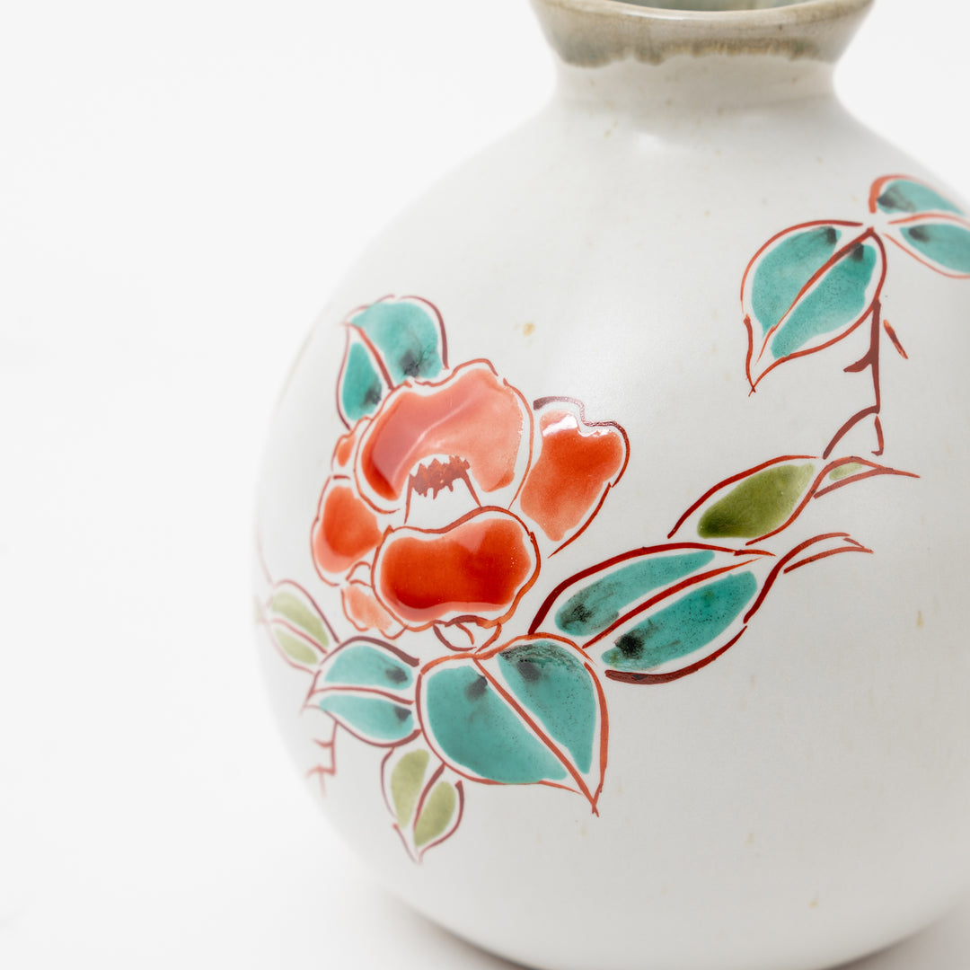 Close-up of a hand-painted Kutani Ware tokkuri (sake flask) showing the detailed red and green floral pattern.