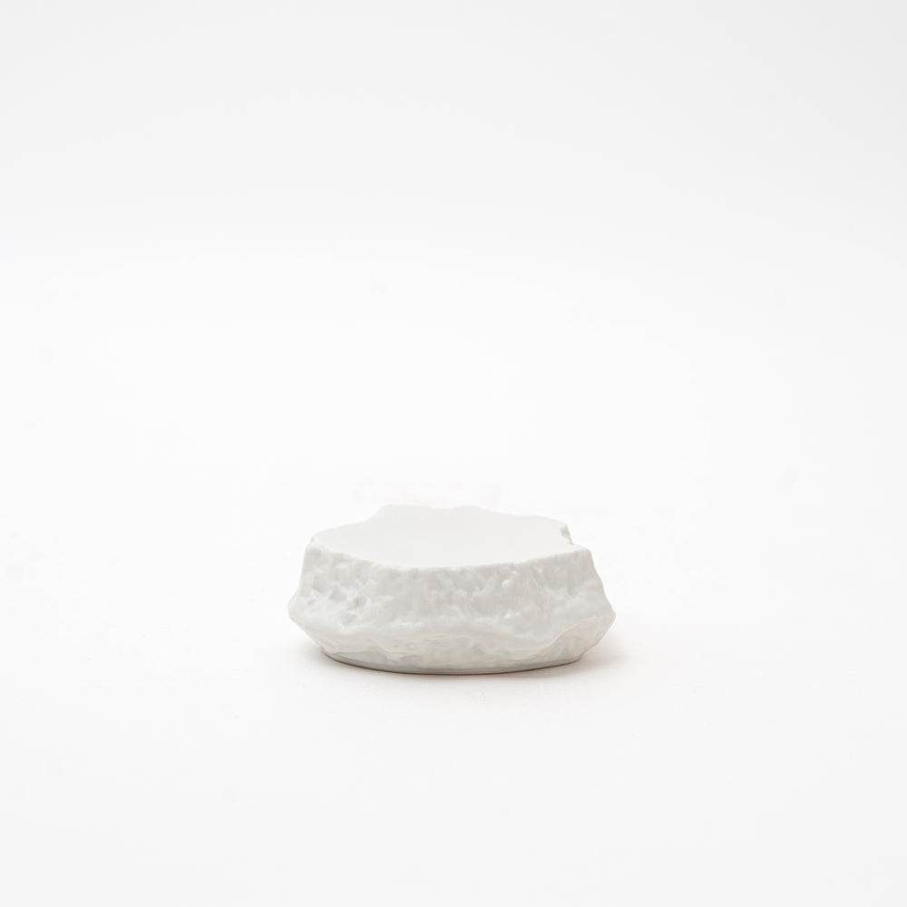 Side view of a white Mikage stone-style ceramic dish, highlighting its irregular, textured shape and unique surface