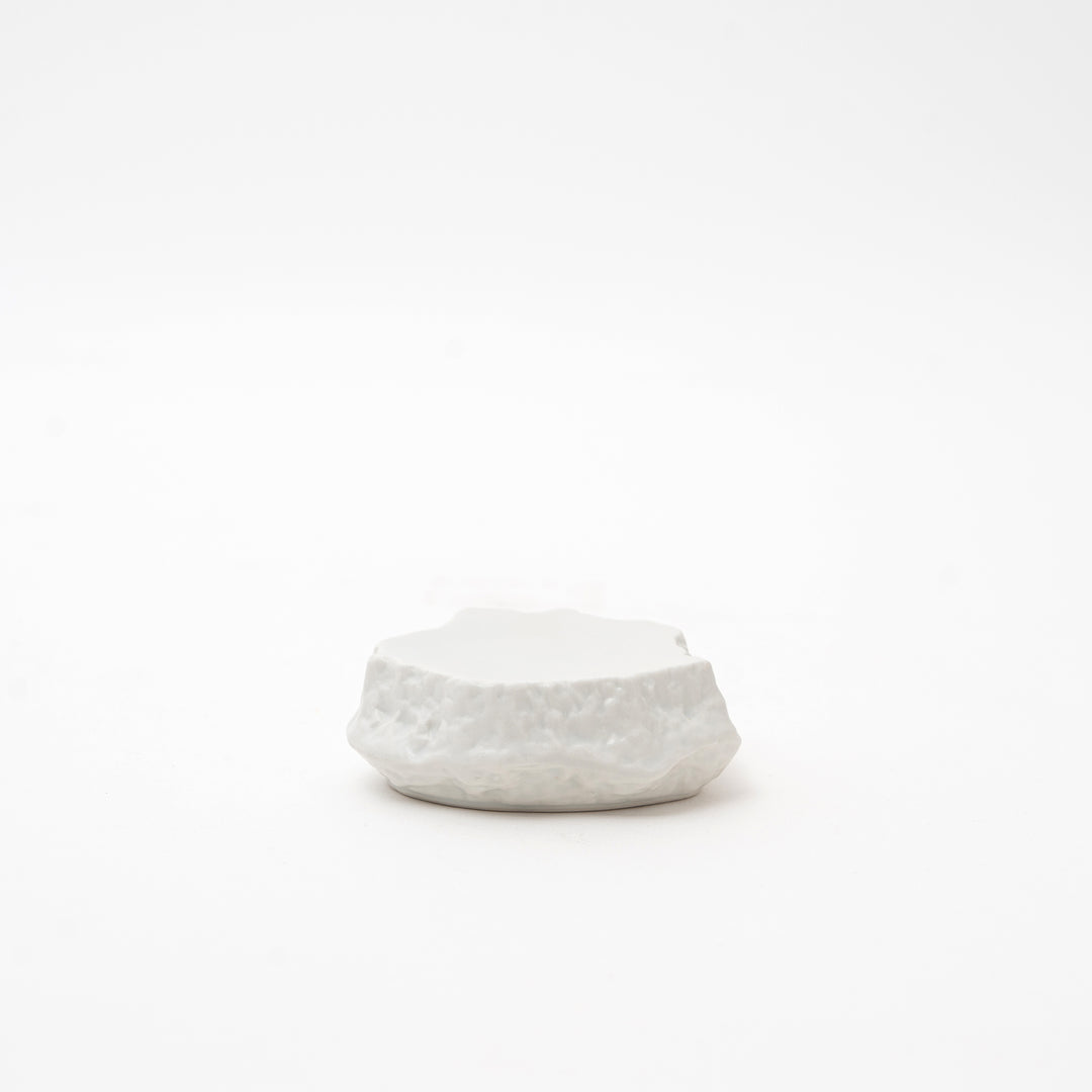Side view of a white Mikage stone-style ceramic dish, highlighting its irregular, textured shape and unique surface