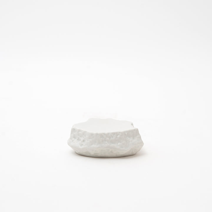 Side view of a white Mikage stone-style ceramic dish, highlighting its irregular, textured shape and unique surface