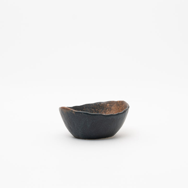 Angled view of the Seto ware small bowl, showcasing its unique asymmetrical shape and the blend of black and rustic brown glazes in a Bizen style.