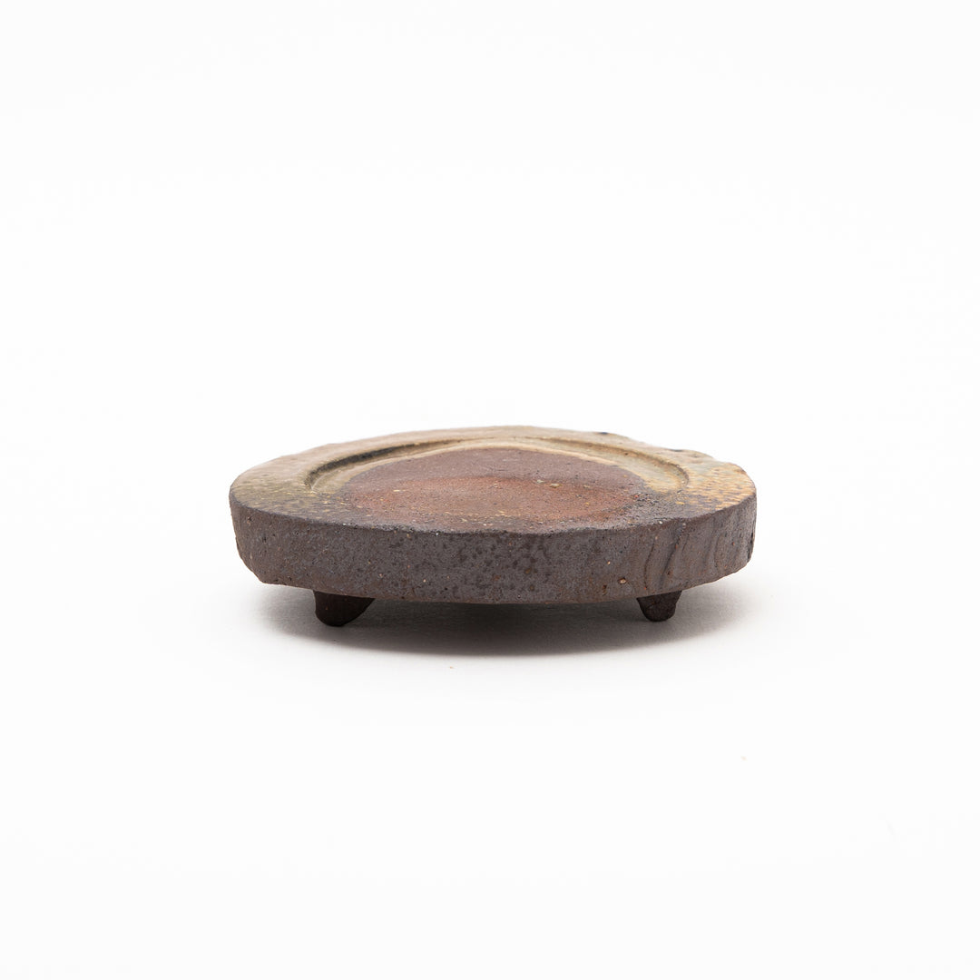 A side view of the Shigaraki ware omakase dish, highlighting its natural texture and the unique three-legged design.