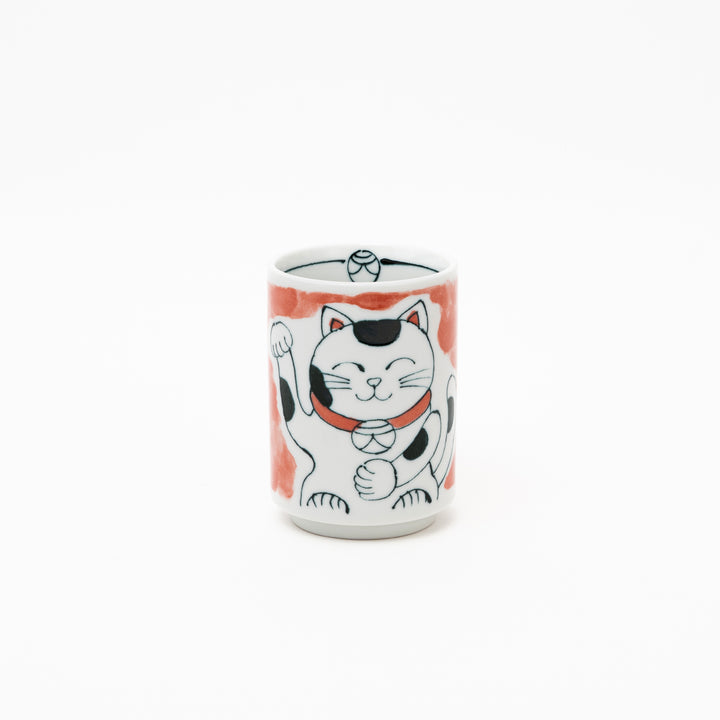 Front view of an authentic Japanese Maneki-Neko lucky cat porcelain cup with a hand-painted white cat, red collar, and red background wash.