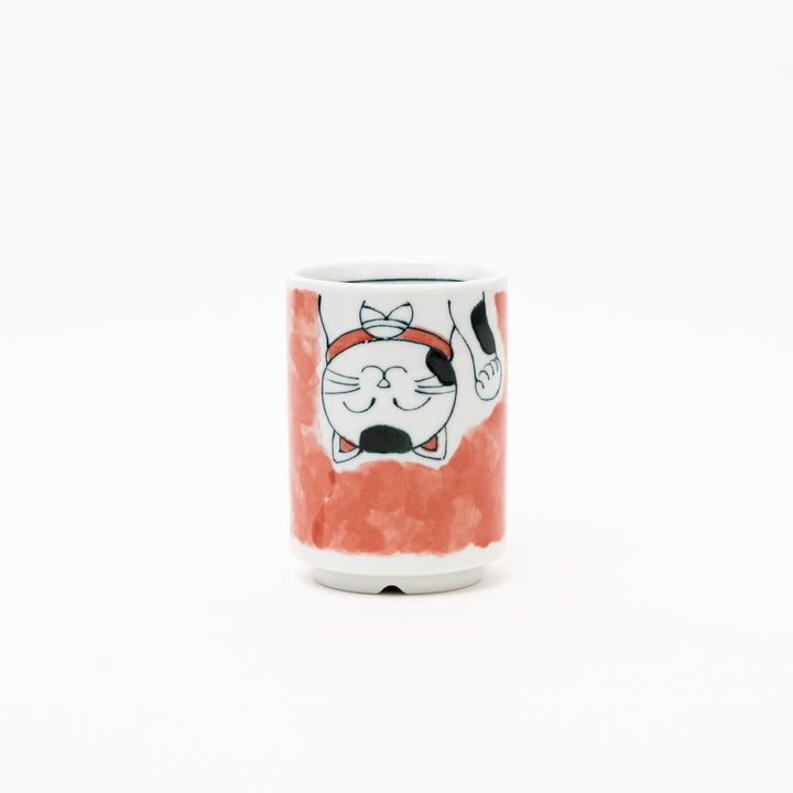 Side view of an authentic Japanese Maneki-Neko lucky cat porcelain cup with a hand-painted white cat, red collar, and red background wash.