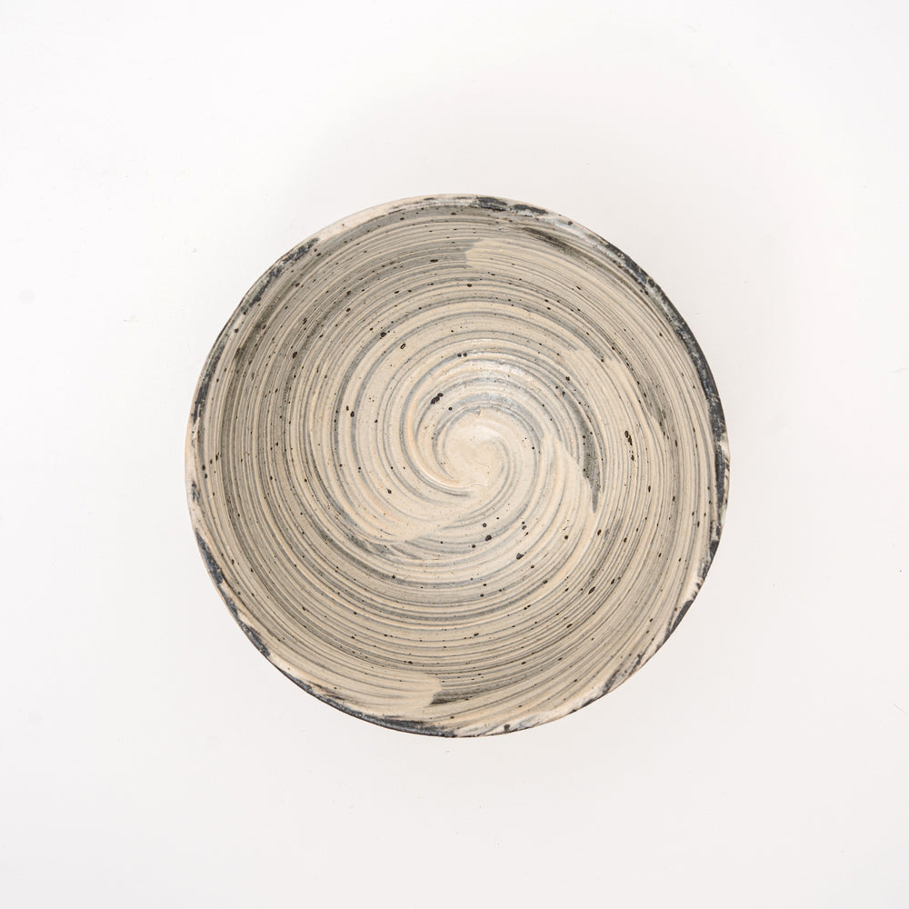 An overhead view of an authentic Shigaraki Yaki bowl, showing the unique spiral pattern and speckled glaze, with a visible Hakeme brushstroke texture.