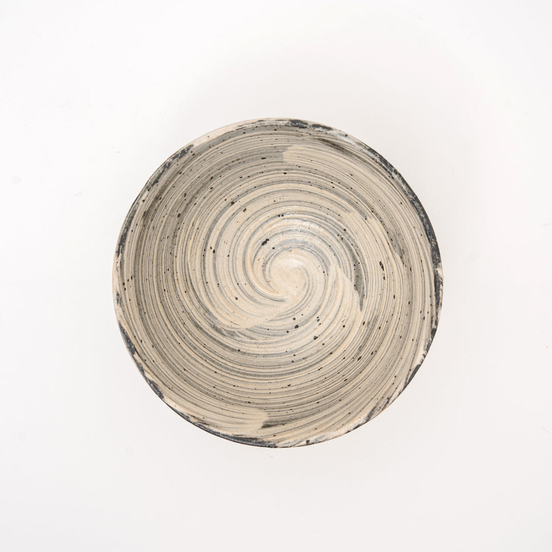 An overhead view of an authentic Shigaraki Yaki bowl, showing the unique spiral pattern and speckled glaze, with a visible Hakeme brushstroke texture.