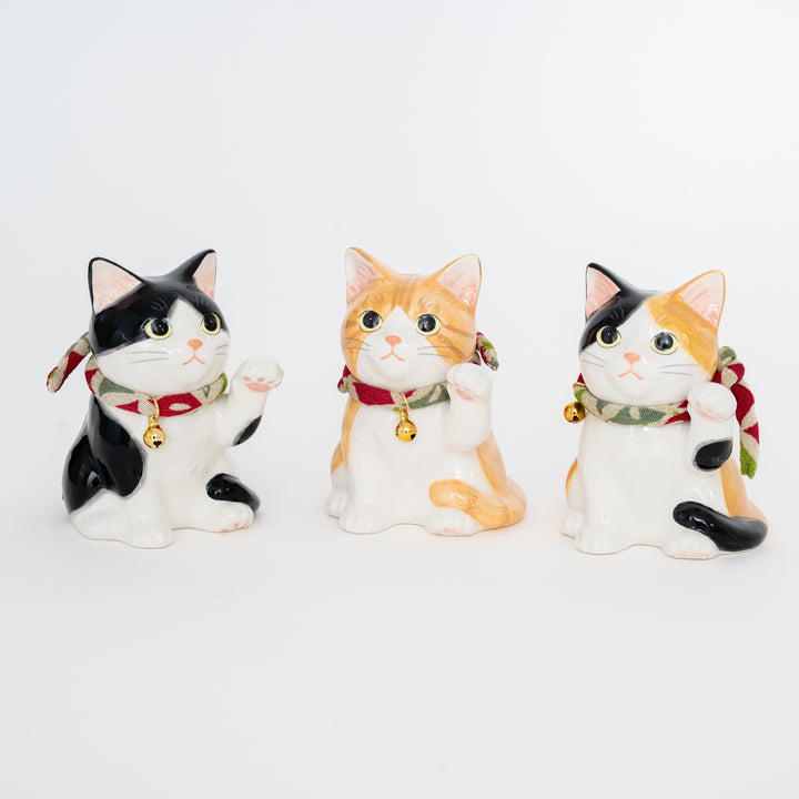 Three ceramic cat figurines with colorful collars on a white background