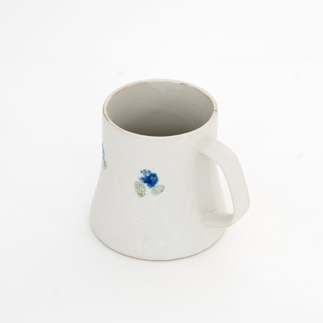 White ceramic mug with a blue floral design on a white background