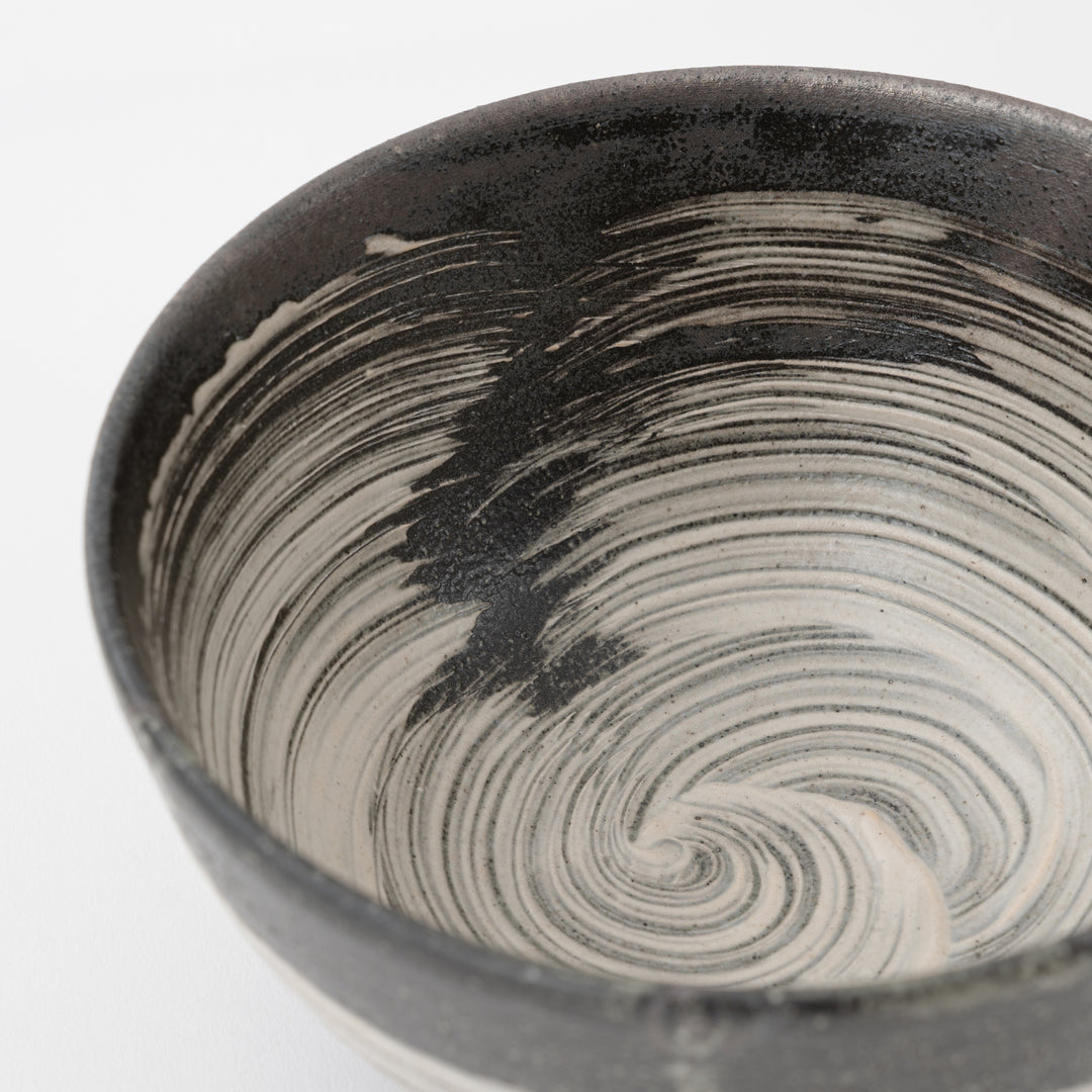 Black and white ceramic bowl with swirling pattern on a white background