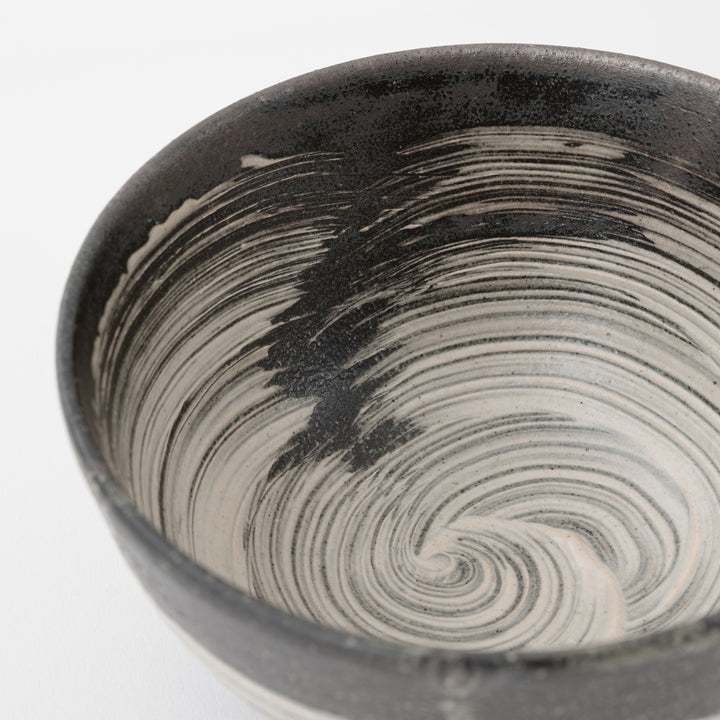 Black and white ceramic bowl with swirling pattern on a white background
