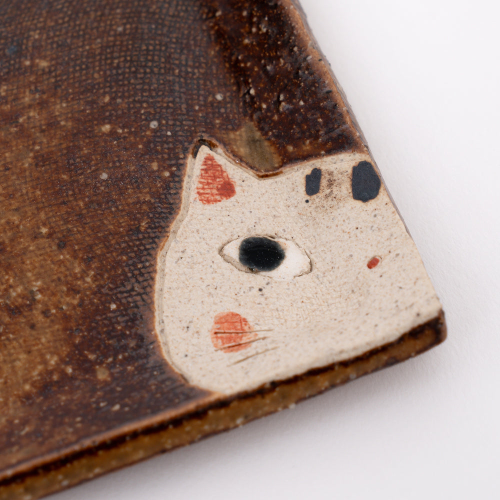 Close-up of peeking cat and striped tail on Japanese ceramic mini dish