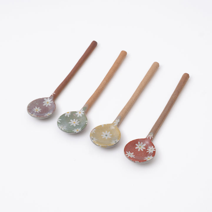 Set of four wooden spoons with floral designs on a white background