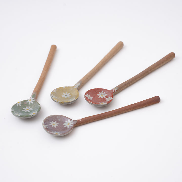 Set of four ceramic spoons with floral patterns on a white background