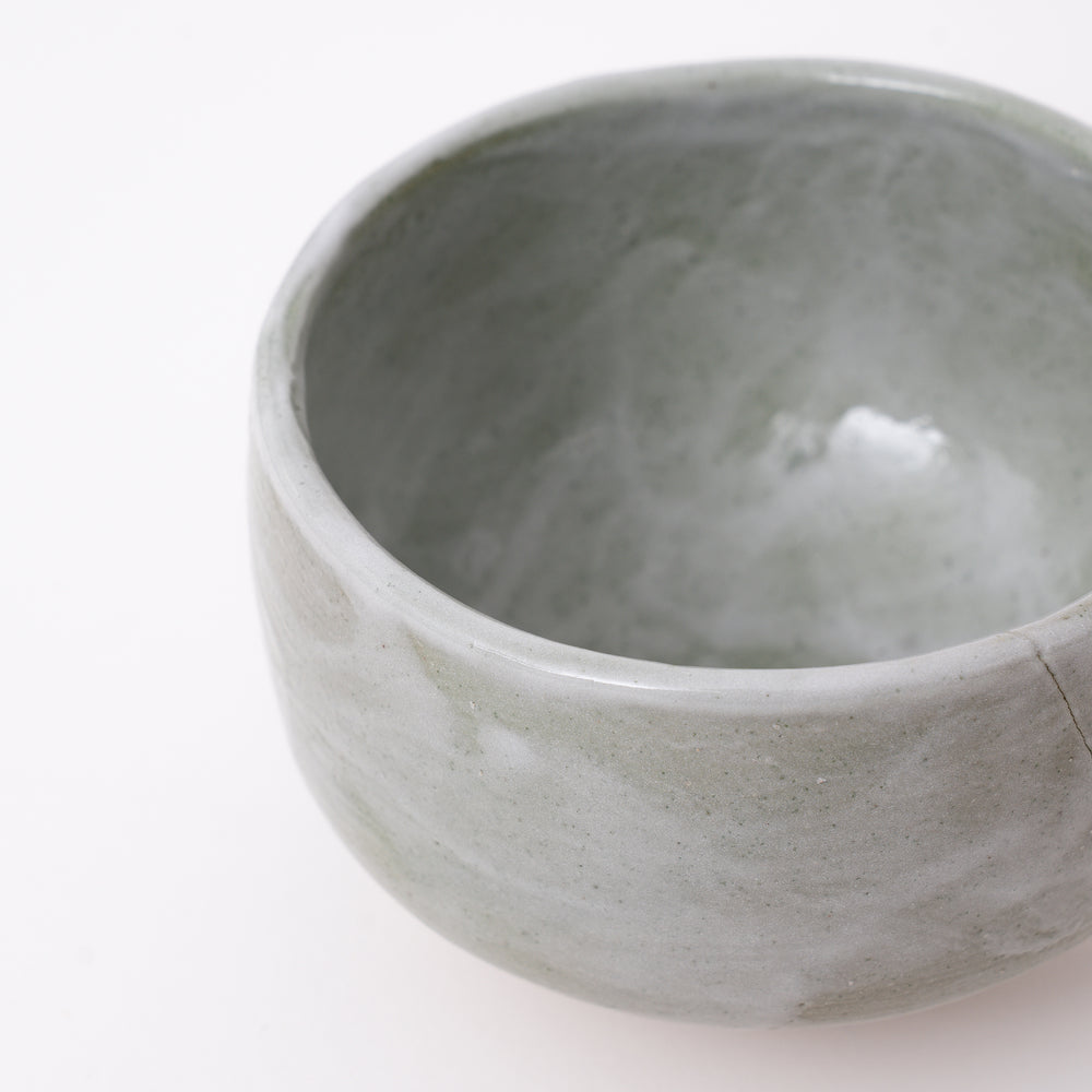 Side view of a handmade Mino Ware Green Shino Matcha Bowl showcasing its rounded shape and flowing glaze.