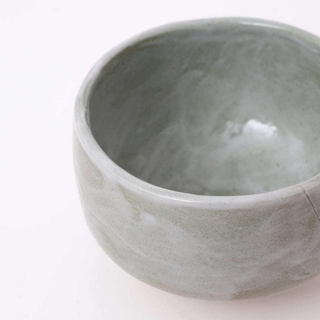 Side view of a handmade Mino Ware Green Shino Matcha Bowl showcasing its rounded shape and flowing glaze.