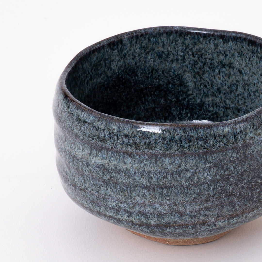 Side view of a handmade Mino Ware Blue Ash Matcha Bowl showcasing its rounded shape and flowing glaze.