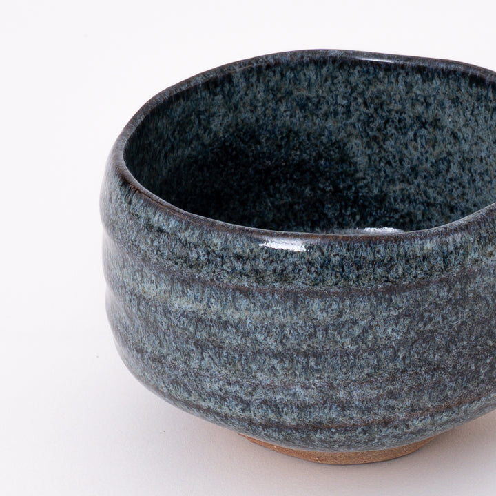 Side view of a handmade Mino Ware Blue Ash Matcha Bowl showcasing its rounded shape and flowing glaze.