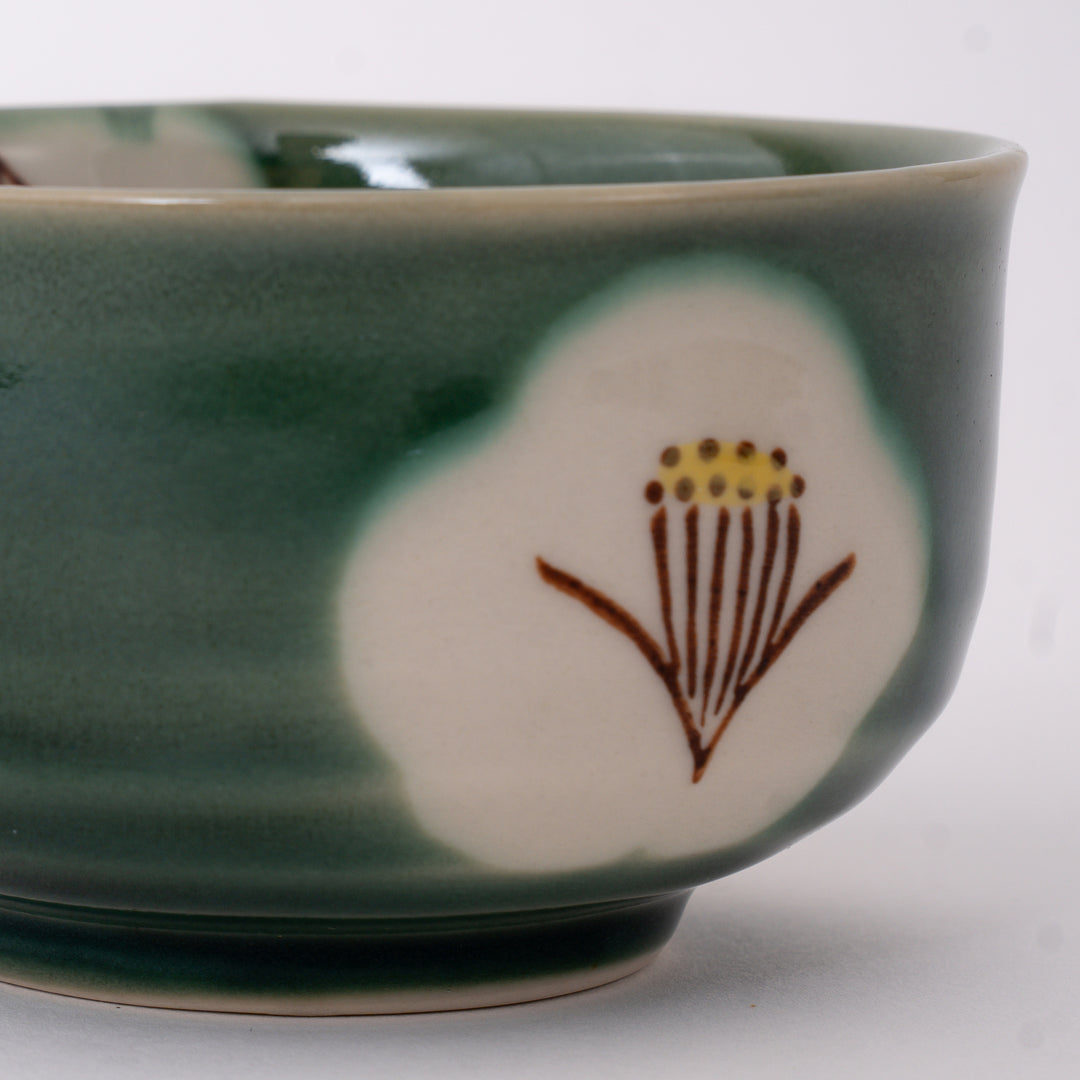 Close-up of the hand-painted camellia motif and glossy Oribe glaze on a handcrafted Seto Ware matcha bowl.
