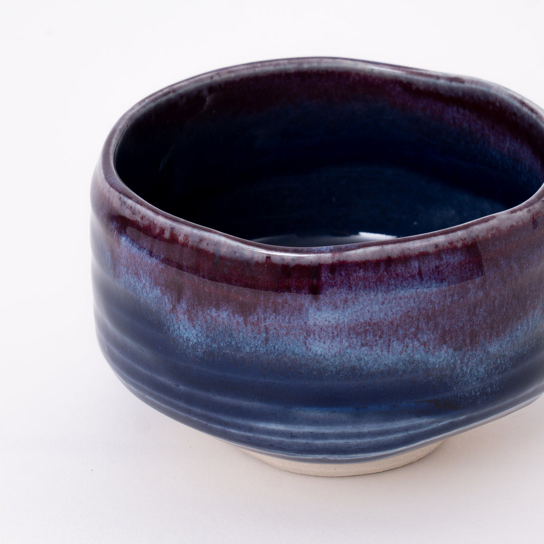 Side view of a handmade Mino Ware Purple Blue Matcha Bowl showcasing its rounded form and flowing glaze.