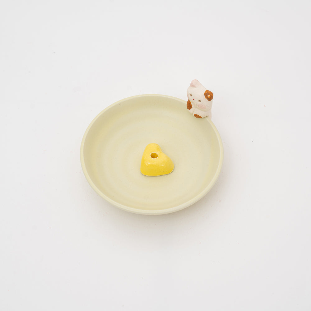 Yellow heart-shaped incense holder with a cat design 