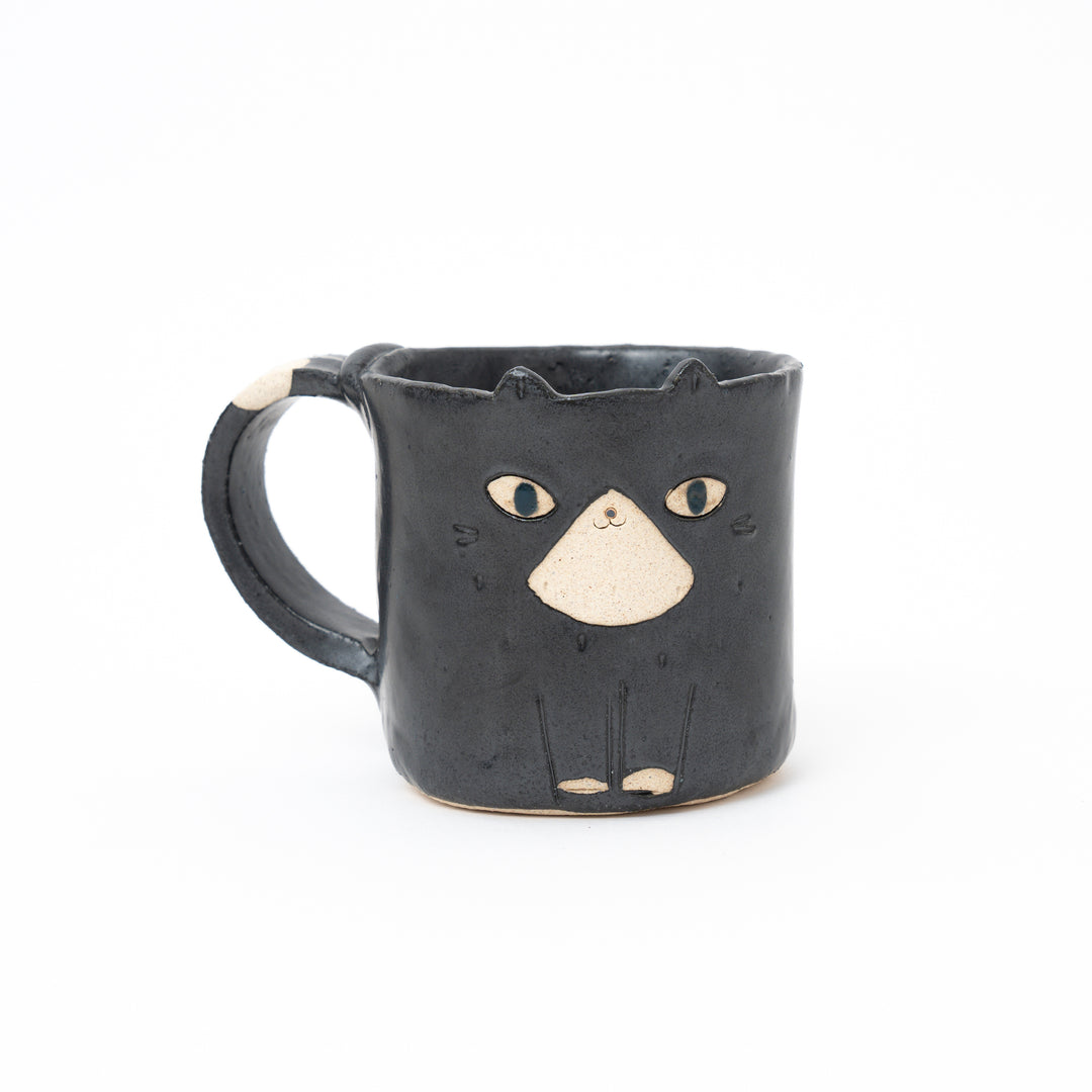 Handcrafted black ceramic cat mug from Japan, featuring a cute white muzzle, eyes, and a white dot on the handle.