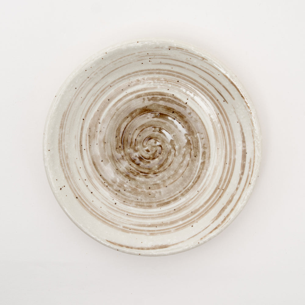 Close-up of spiral pattern ceramic sauce dish showing concentric circles and speckled glaze texture